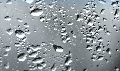 rain drops on windshield of a car with out of focus background (driving in wet stormy weather) storm drop grey gray 