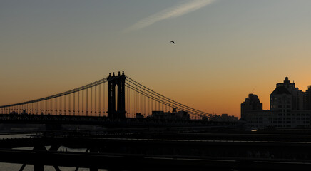 view of new york city skyline from brooklyn bridge (manhattan skyscrapers nyc) travel tourism destination landmark sunrise dawn (dark sun rising) suspension cables colorful sky beautiful photography