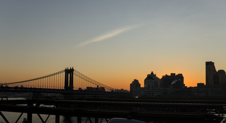 view of new york city skyline from brooklyn bridge (manhattan skyscrapers nyc) travel tourism destination landmark sunrise dawn (dark sun rising) suspension cables colorful sky beautiful photography