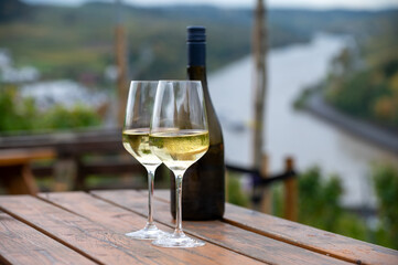 Glasses of white dry riesling wine made on Moselle river valley in Germany or Luxembourg, view on...