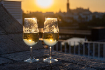 Drinking of cava or champagne sparkling wine on outdoor roof terrace with view on central part of old Sevilla, Andalusia, Spain sunset