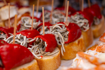 Typical snack of Basque Country, pinchos or pinxtos skewers with small pieces of bread, sea food, eggs, cheese, jamon served in bar in San-Sebastian or Bilbao, Spain, close up
