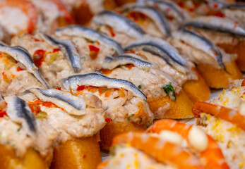 Typical snack of Basque Country, pinchos or pinxtos skewers with small pieces of bread, sea food, eggs, cheese, jamon served in bar in San-Sebastian or Bilbao, Spain, close up