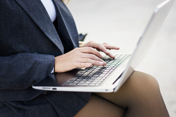 A professional woman types on her laptop outdoors, showcasing her vibrant career and confidence