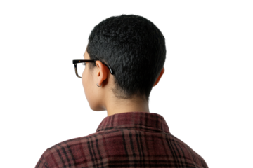 Young man with tousled hair wearing a plaid shirt turns to look over his shoulder against a plain white background