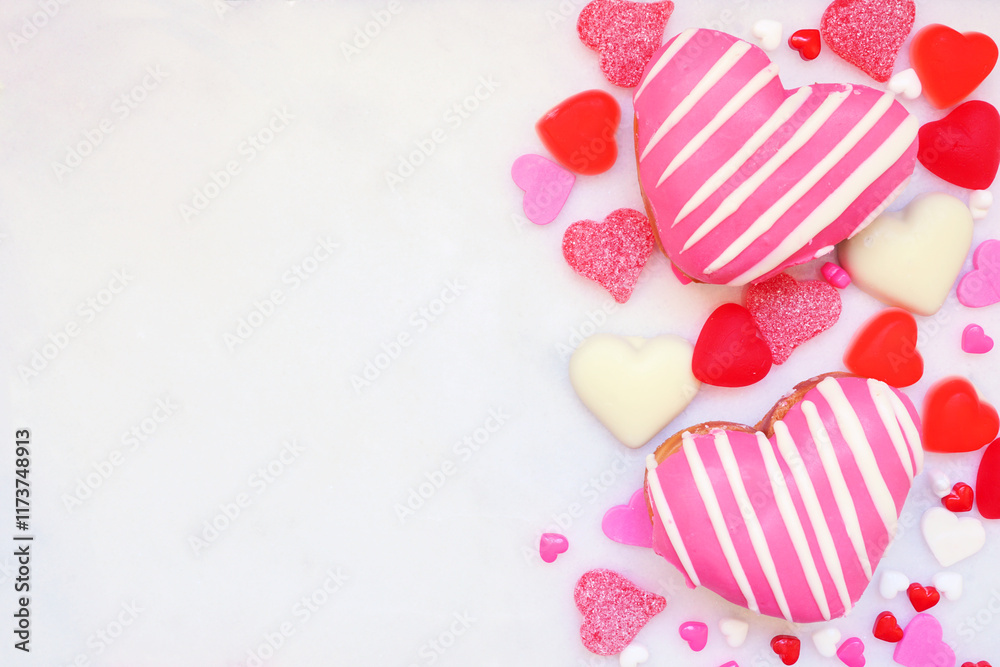 Poster valentines day heart shaped sweets side border with donuts and candies. top view on a white marble b