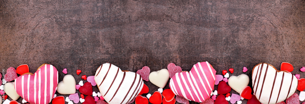 Aufkleber valentines day heart shaped sweets bottom border with donuts and candies. top down view on a dark st