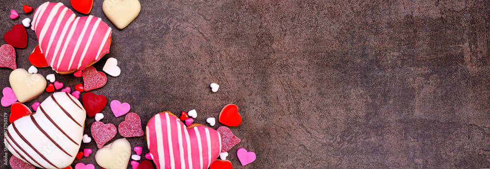 Aufkleber Valentines Day heart shaped sweets corner border with donuts and candies. Top view on a dark stone banner background with copy space.