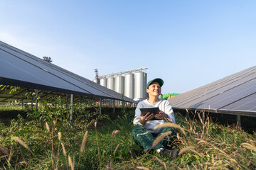 Female farmer with digital tablet on a modern farm using solar panels. Agricultural silos in the...
