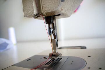A detailed close-up of the sewing machine needle and stitch plate, capturing the precision of this essential tool for crafting, tailoring, and fashion design. This image emphasizes the intricacies of