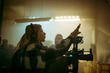 A female director at work on the set. The director works with a band or with a speaker during the filming of a movie, commercial, or television series. The crew, equipment, and crew. 