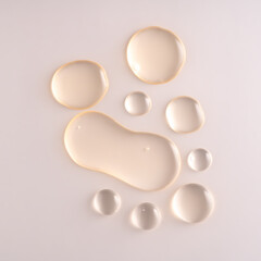 Oil serum drops. Liquid droplets on beige color background. Cosmetic product with bubbles closeup