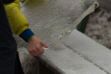 Hand Pulling a Piece of Ice from River or Lake. Close-up of a hand reaching into cold water to retrieve a piece of ice. Raw interaction with nature, crystal clear beauty of frozen water.