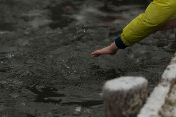 Hand Pulling a Piece of Ice from River or Lake. Close-up of a hand reaching into cold water to retrieve a piece of ice. Raw interaction with nature, crystal clear beauty of frozen water.