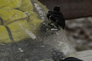 Hand Pulling a Piece of Ice from River or Lake. Close-up of a hand reaching into cold water to retrieve a piece of ice. Raw interaction with nature, crystal clear beauty of frozen water.
