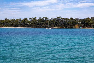 A serene view of a calm, turquoise bay with gentle ripples on the water's surface.