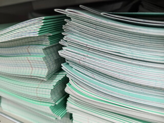 Stacks of neatly organized green notebooks in a classroom setting