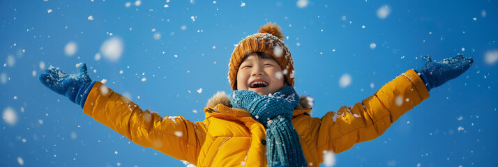 Joyful child enjoying snowfall in a winter landscape under clear blue sky during a sunny day.