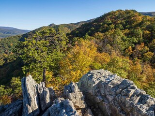 View over wooded mountain landscape in fall colors with cliffs in the foreground at from the summit...