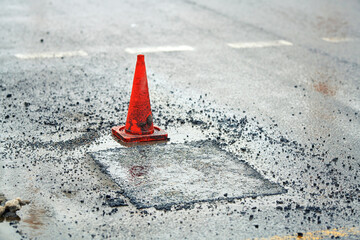 Traffic cone placed on the road during asphalt pavement patching, pothole repair work, new asphalt...
