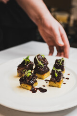 A delicious gourmet dish featuring tender meat topped with rich sauce, served on a bed of polenta and garnished with microgreens, elegantly plated for a fine dining experience.