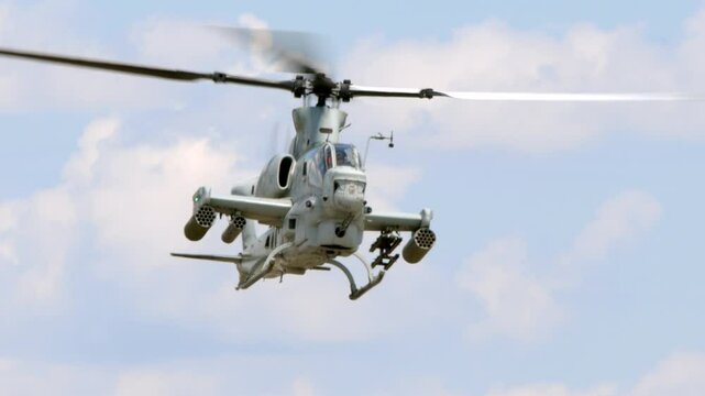 A United States Marines Bell AH-1 Cobra attack helicopter hovers and turns toward the camera in this slow motion shot.