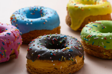 Colorful glazed donuts with sprinkles on white background.