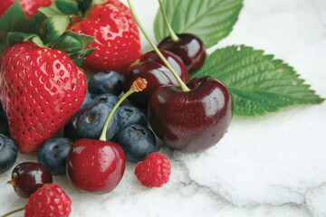 A close-up of fresh cherries, strawberries, and blueberries with green leaves, emphasizing their glossy textures and vibrant natural colors on a marble surface.
