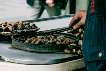 Man roasting chestnut tourist outdoor town, grilled food, snacking street food