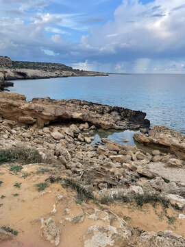 Rocky Coastline and Clear Waters of Cape Greco, Cyprus, Under Dramatic Cloudy Skies&mdash;A Pristine Mediterranean Escape with Stunning Natural Beauty