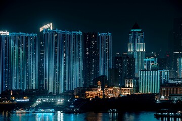 Fototapeta premium Illuminated skyscrapers at night reflecting on a river.