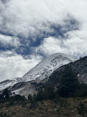 Snow-capped mountain under cloudy sky