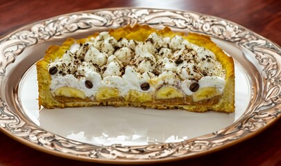 Authentic banoffee cake with banana and caramel sauce filling sprinkled with grated dark chocolate and coffee . English traditional pie