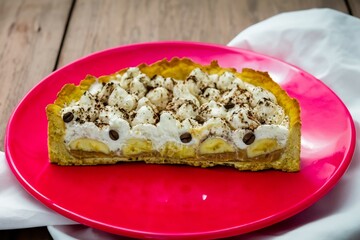 Authentic banoffee cake with banana and caramel sauce filling sprinkled with grated dark chocolate and coffee . English traditional pie