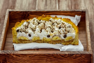 Authentic banoffee cake with banana and caramel sauce filling sprinkled with grated dark chocolate and coffee . English traditional pie