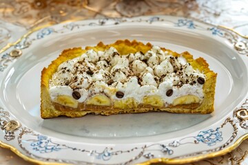 Authentic banoffee cake with banana and caramel sauce filling sprinkled with grated dark chocolate and coffee . English traditional pie