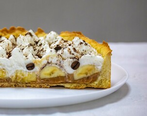 Authentic banoffee cake with banana and caramel sauce filling sprinkled with grated dark chocolate and coffee . English traditional pie