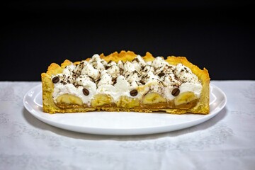 Authentic banoffee cake with banana and caramel sauce filling sprinkled with grated dark chocolate and coffee . English traditional pie