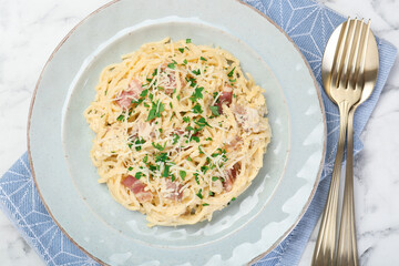 Delicious pasta Carbonara with bacon served on white marble table, flat lay