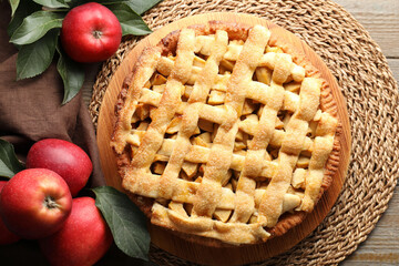 Flat lay composition with tasty homemade apple pie, fruits and leaves on wooden table