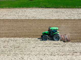 Fototapeta premium tractor in the field plowing the land for spring crops