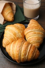 Tasty fresh croissants and drink on wooden table, closeup