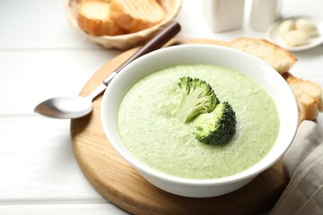 Delicious broccoli cream soup served on white wooden table, closeup
