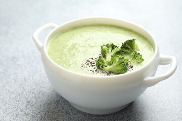 Delicious broccoli cream soup in bowl on light table, closeup