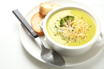 Delicious broccoli cream soup served on white wooden table, closeup