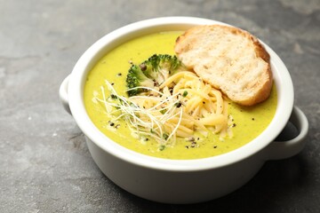 Delicious broccoli cream soup and crouton in bowl on gray textured table, closeup