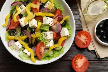 Delicious fresh Greek salad served on wooden table, flat lay