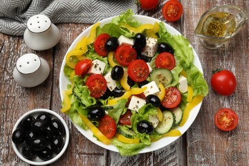 Delicious fresh Greek salad and ingredients on wooden table, flat lay