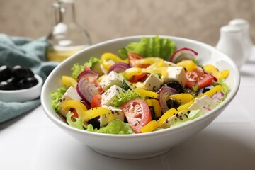 Delicious fresh Greek salad in bowl on white table, closeup