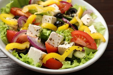 Delicious fresh Greek salad in bowl on wooden table, closeup